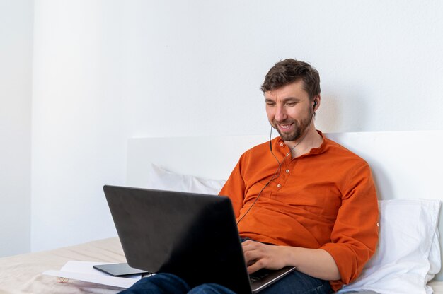 Uomo bello sorridente che per mezzo del computer portatile a casa