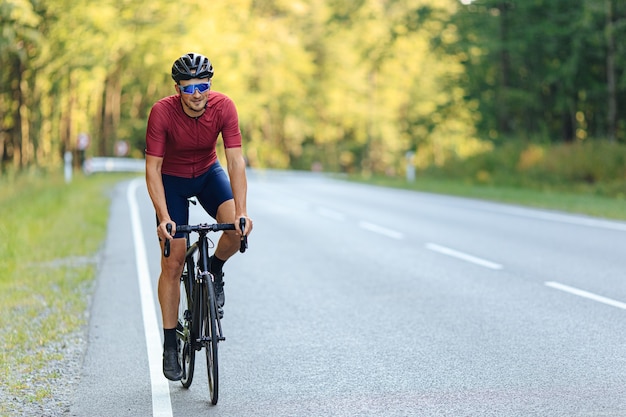 도로 자전거를 타는 동안 보호용 헬멧과 미러 안경을 쓰고 웃는 잘 생긴 남자