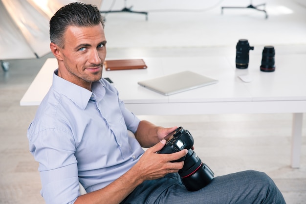 Smiling handsome photographer using camera in studio