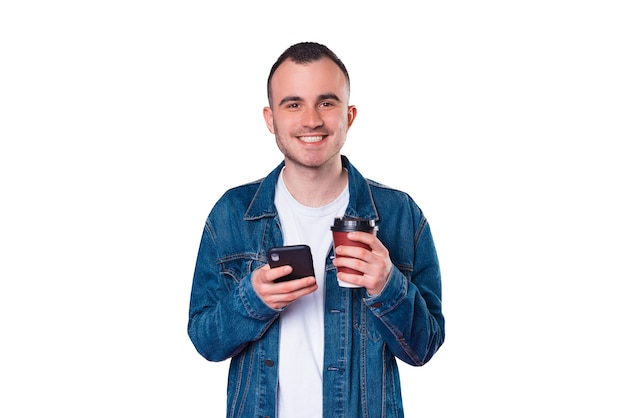 Smiling handsome young man using smartphone and drinking cup of coffee