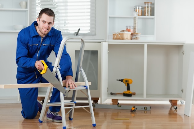 Smiling handyman cutting a wooden board