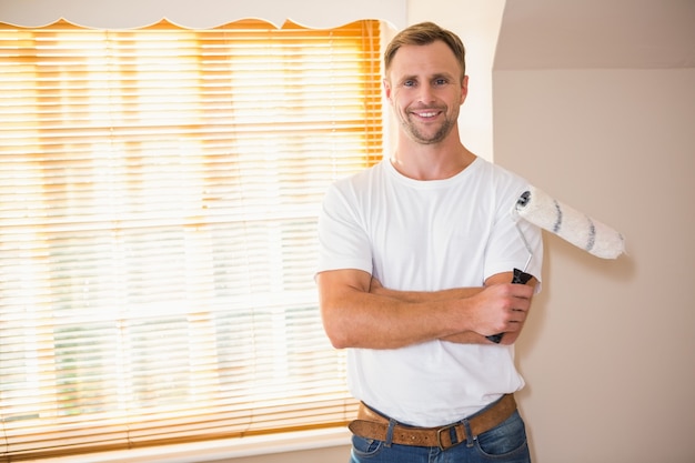 Smiling handyman posing while holding a paintbrush