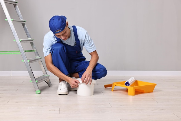 smiling handyman preparing to painting wall indoors
