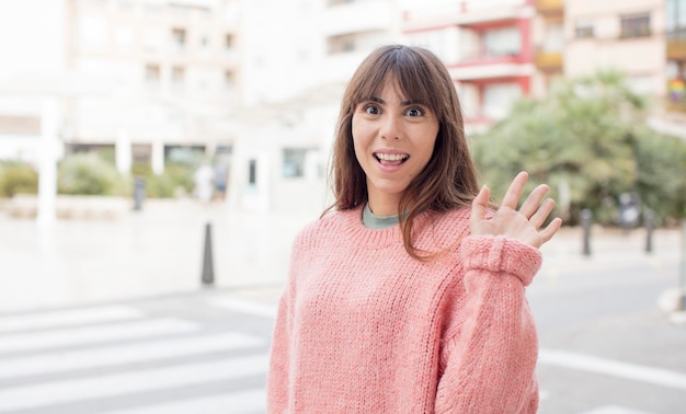 Sorridendo allegramente e allegramente agitando la mano dandoti il benvenuto e salutandoti o salutandoti