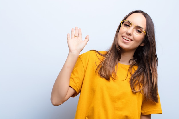 Foto sorridendo felicemente e allegramente, agitando la mano, dandoti il benvenuto e salutandoti o salutandoti