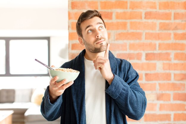 Foto sorridendo felicemente e sognando ad occhi aperti o dubitando, uomo che guarda di lato