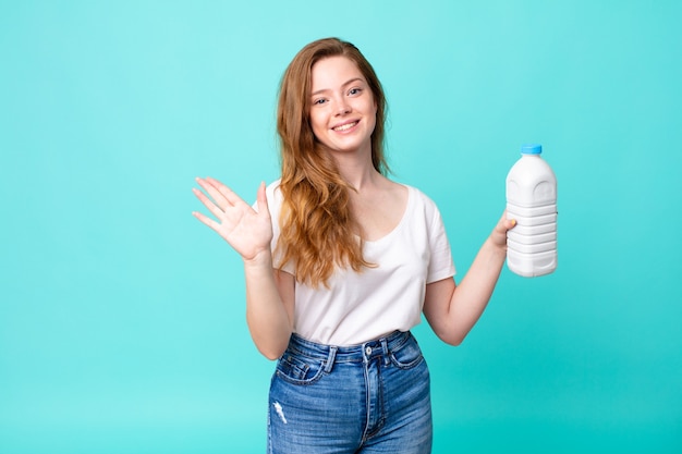 Smiling happily, waving hand, welcoming and greeting you and holding a milk bottle