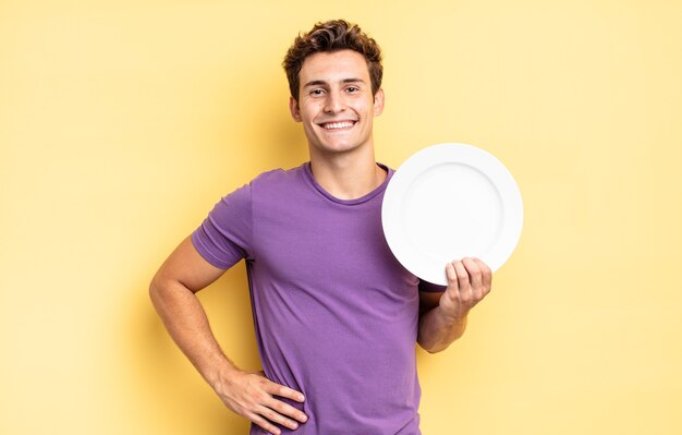 Smiling happily with a hand on hip and confident, positive, proud and friendly attitude. empty plate concept