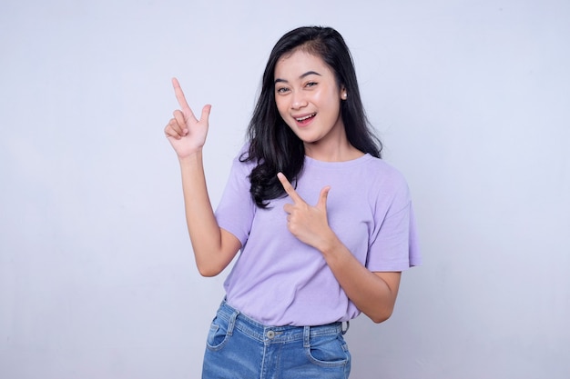 Smiling happy asian woman with her left finger pointing isolated on light white banner background with copy space