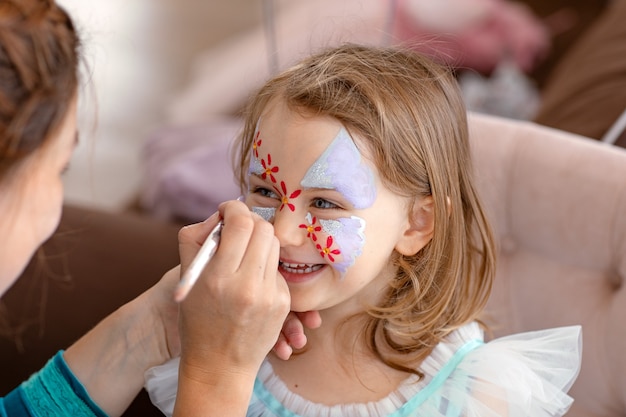 Smiling happy child with face art aqua grimm on birthday or halloween party face art painting