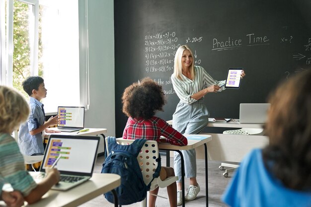 Photo smiling happy cute teacher having mathematics lesson class sitting on desk