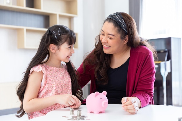 笑顔の幸せな娘の子供は、貯金箱で教育と経済のためにお金を節約するためにコインを収集します