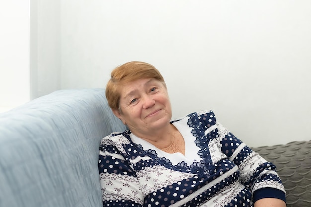 Smiling happy elderly woman at home sitting on the couch a\
cheerful person grandmother