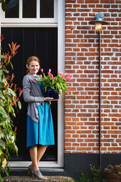 Smiling happy girl holding a vase with pink tulips