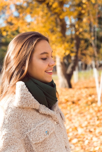 Smiling happy girl walking in autumn at fall park yellow leaves