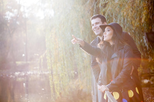 Sorridente coppia gourgeous felice che cammina nel parco d'autunno vicino a un lago