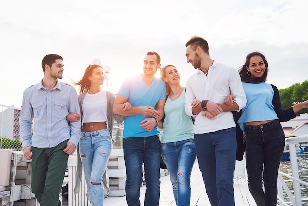 Smiling happy group of friends posing for the camera outdoors on the beach pier