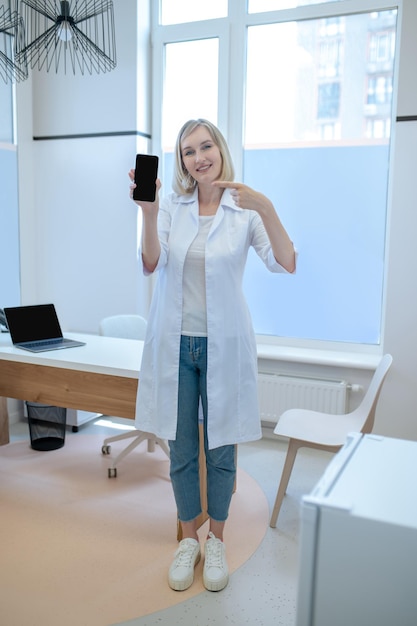 Smiling happy healthcare worker showing off her cellphone