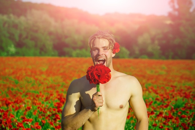 Smiling happy man in field of red poppy seed