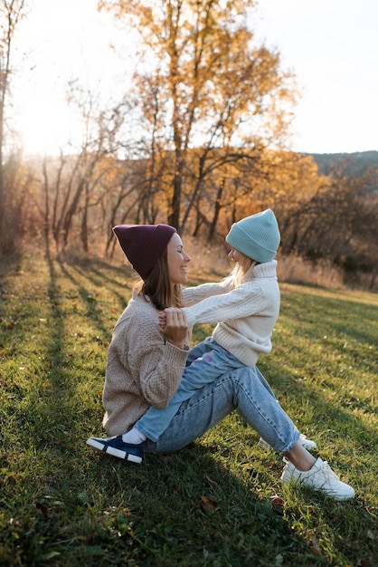 Smiling happy mother holding little baby girl wear casual clothes in autumn park outdoor Family content Motherhood