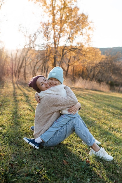 Smiling happy mother holding little baby girl wear casual clothes in autumn park outdoor Family content Motherhood