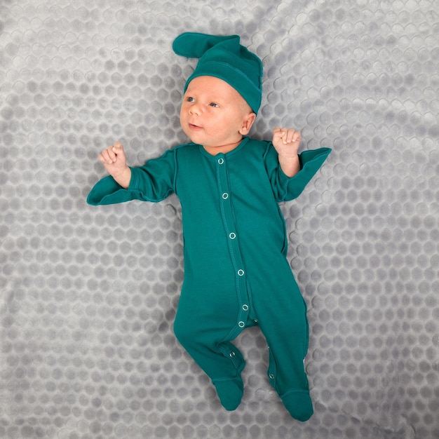 Photo smiling happy newborn infant one month baby in the green clothes on bed bright airy copy space childhood