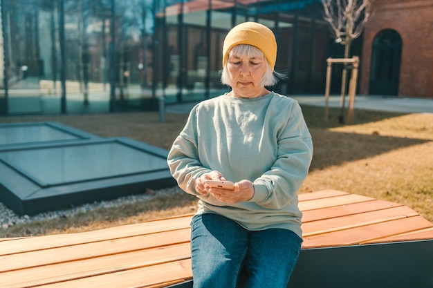 Smiling happy woman s wearing a yellow hat sitting on bench in city spring park outdoors resting use