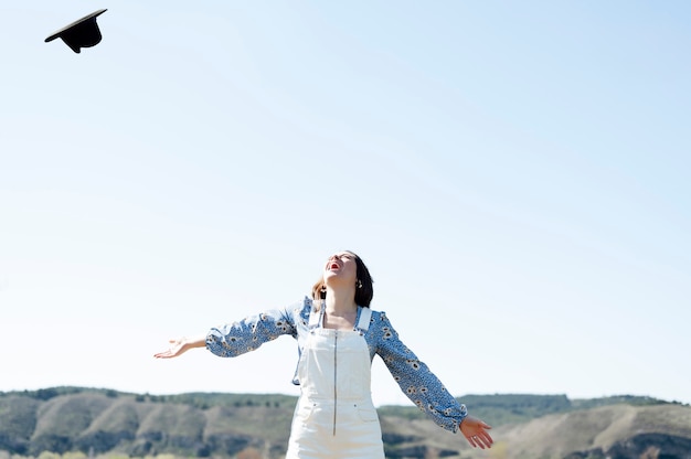 写真 フィールドで空に帽子を投げて幸せな女の笑顔