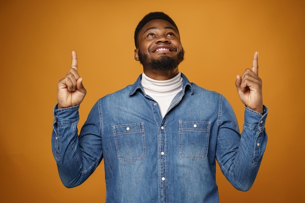 Smiling happy young african american man pointing up to copy space