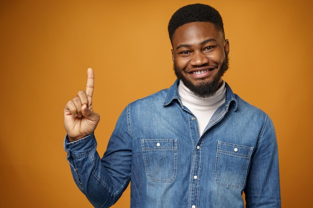 Smiling happy young african american man pointing up to copy space