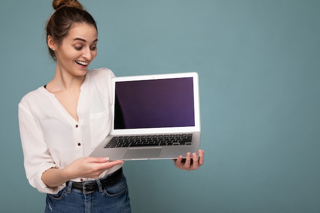 고립 된 캐주얼 스마트 옷을 입고 재미 netbook보고 컴퓨터 노트북을 들고 웃는 행복 한 젊은 여자