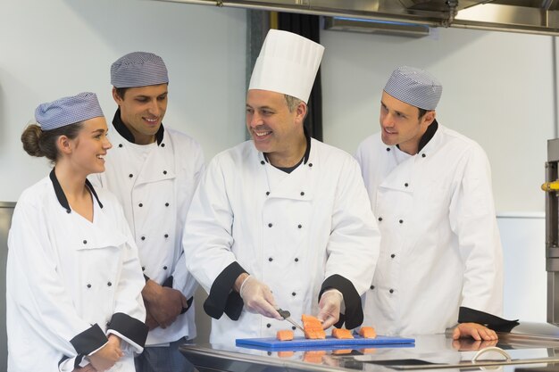 Smiling head chef teaching how to fillet salmon