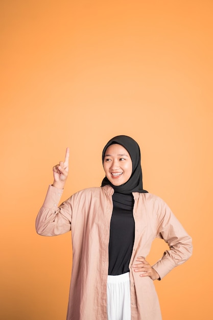 Smiling hijab woman with finger pointing up hand gesture