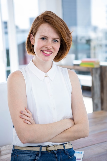 smiling hipster business woman standing in her office with her arms folded