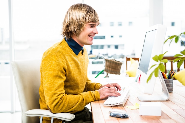 Smiling hipster businessman using his computer in office