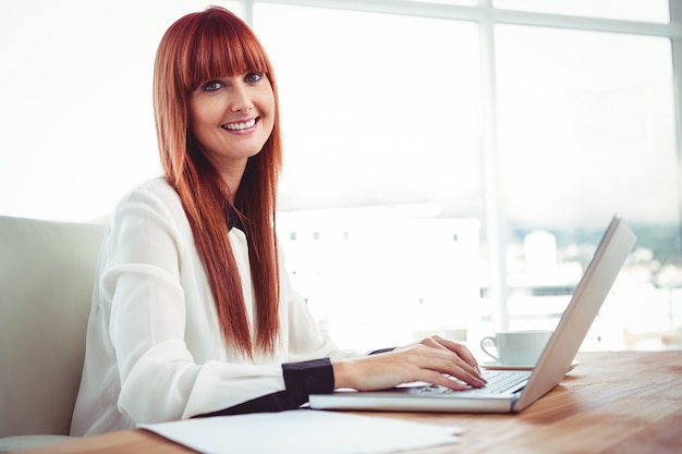 Smiling hipster businesswoman using her laptop