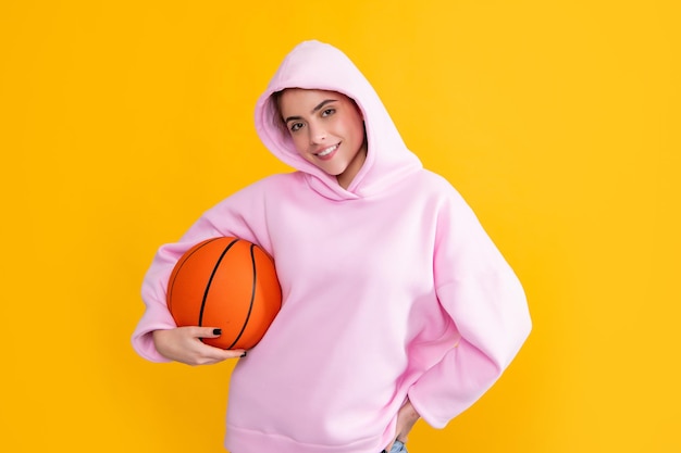 黄色の背景にバスケットボールのボールと笑顔の流行に敏感な学生の女の子