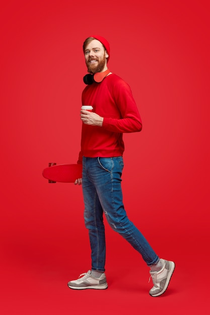 Sorridente hipster con drink e skateboard