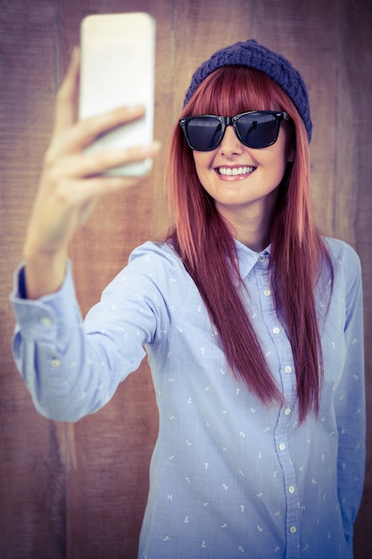 Smiling hipster woman taking selfie