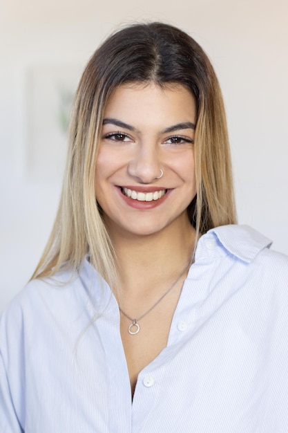 Smiling Hispanic student in shirt looking at camera. Positive pretty girl with piercing wearing silver jewelry. Young woman concept