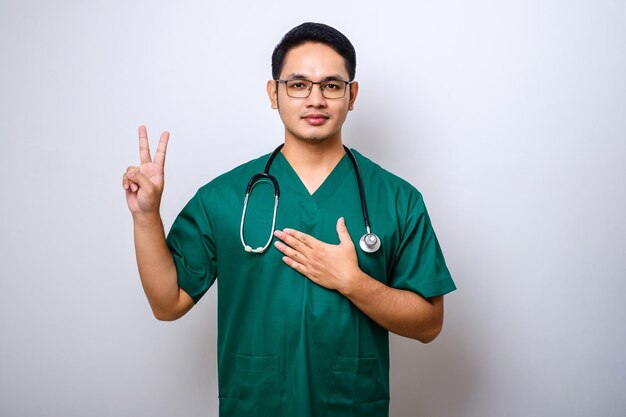 Smiling honest asian male nurse or doctorraising one arm and hold hand on heart while promise oath to patient