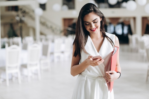 Smiling hostess using smartphone