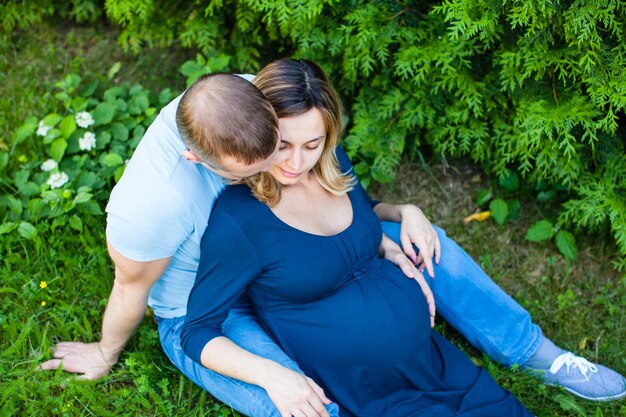 Smiling husband with pregnant wife is resting on the nature