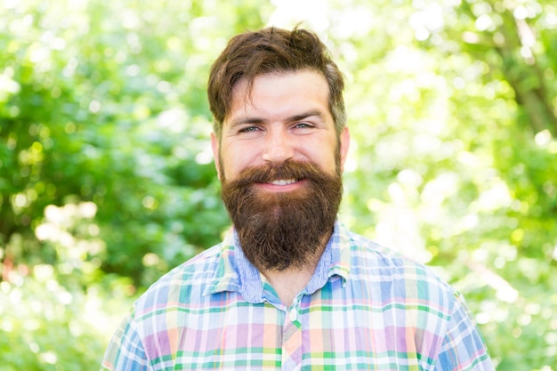 Sorridere aumenta la felicità uomo barbuto con una faccia sorridente allegra sul paesaggio naturale hipster sorridente che indossa baffi e barba alla moda nelle giornate estive sono sempre sorridente e felice