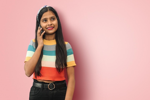 Smiling Indian Asian girl talking over the phone looking up Mock up copy space