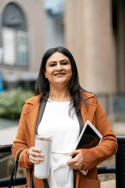 Smiling Indian business woman holding digital tablet bottle of water looking at camera