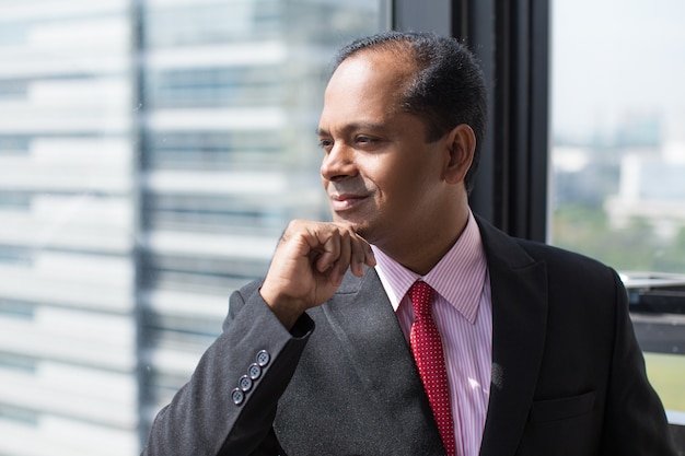 Smiling Indian businessman looking out of window