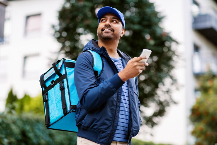Photo smiling indian delivery man with bag and phone