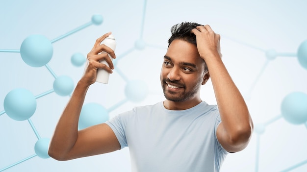 smiling indian man applying hair spray