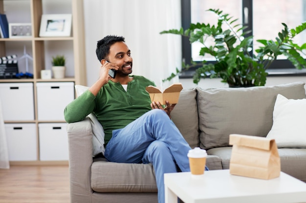 smiling indian man eating takeaway food at home